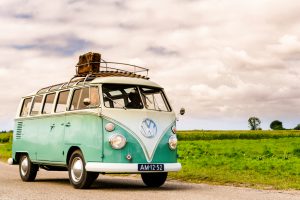 Beekbergen, The Netherlands - September 6, 2015: 1950s Volkswagen Samba or Sunroof Deluxe classic car. Two people are sitting inside the VW that is driving on a country road.